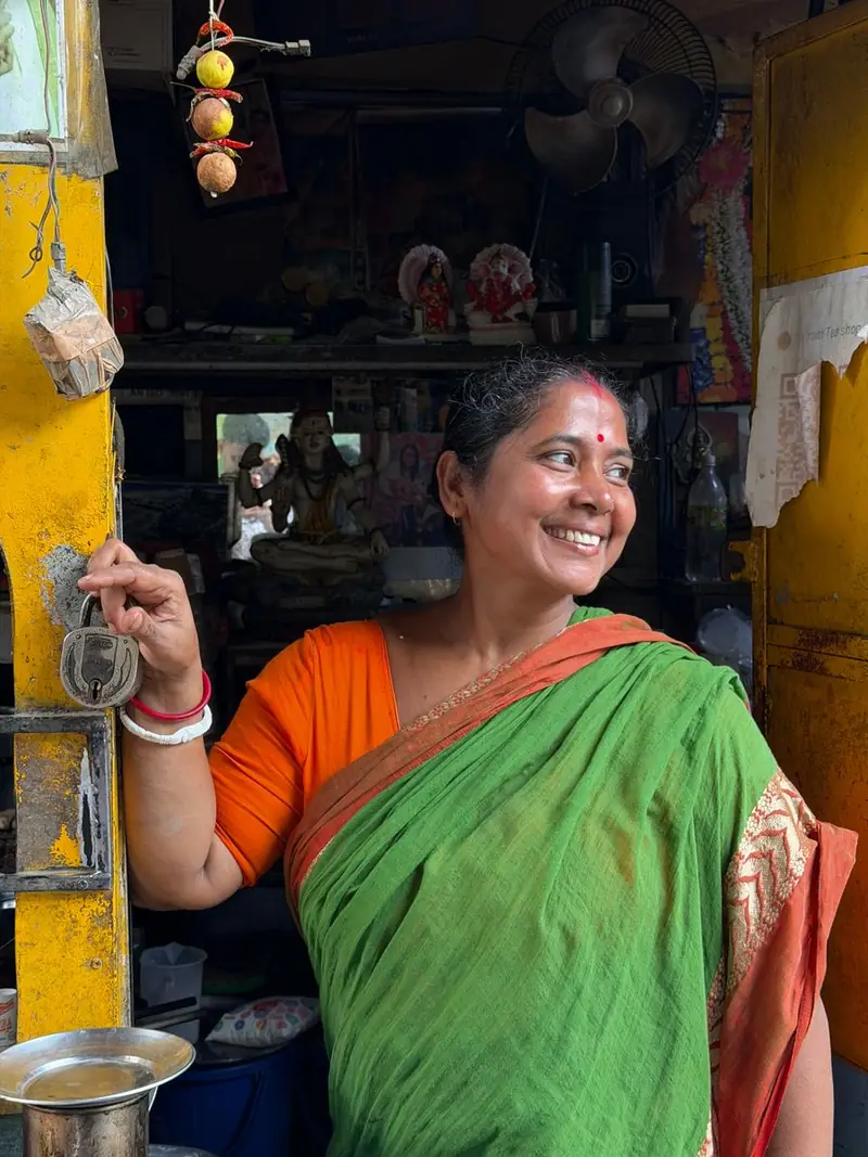 A woman smiling at the doorway of her shop