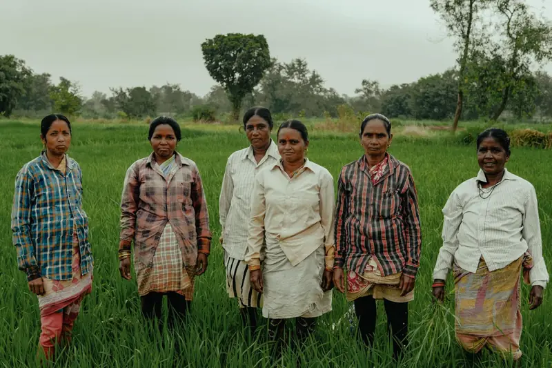 A group of women standing together in a green field